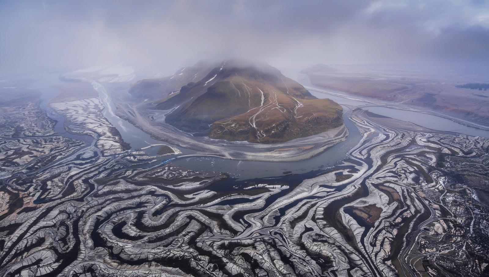 Aerial view of interconnected rivers flowing around a mountain system